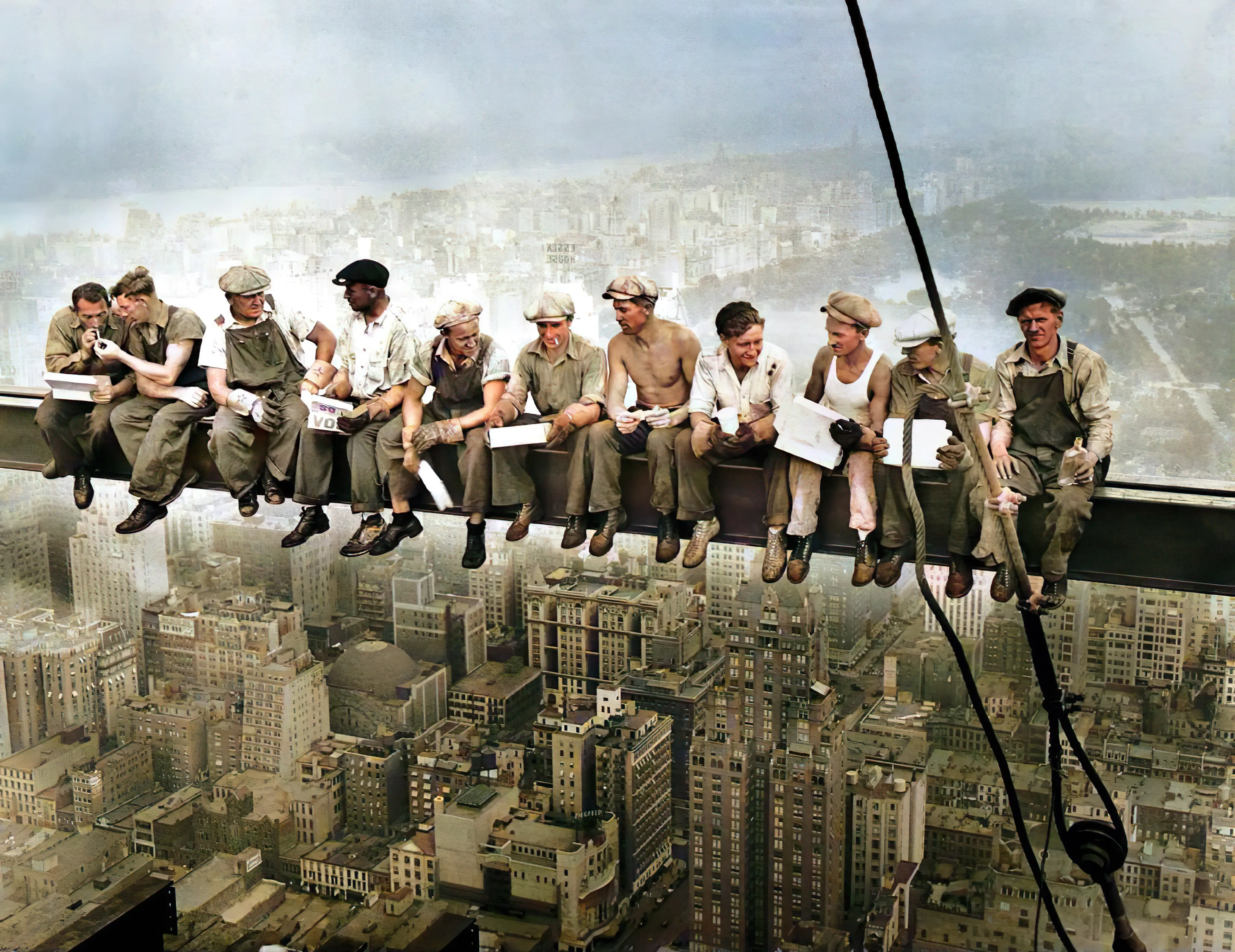 Construction workers sitting on steel beam high above city